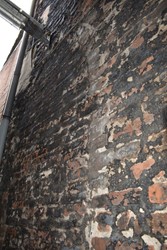 <p>Het onderste deel van de linker zijgevel aan de Zeepziedersstreeg dateert uit de 14e eeuw en is herkenbaar aan een groot formaat baksteen met een 10-lagenmaat van 76-80 cm. In de muur bevinden zich meerdere bouwsporen die vanwege de afwerking/beperkte waarneembaarheid slecht geduid kunnen worden. </p>
